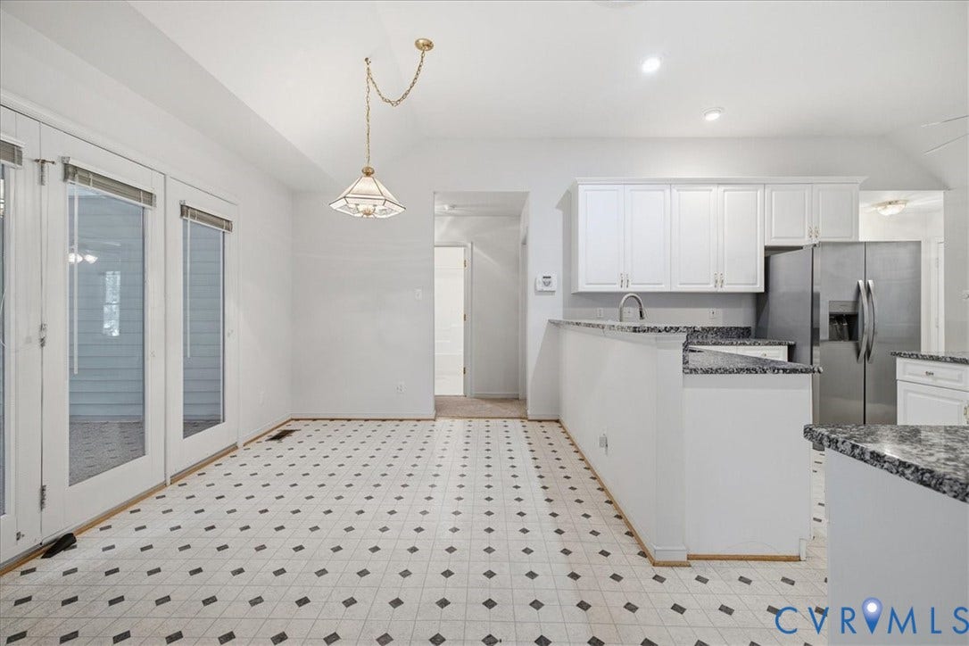 Kitchen with white cabinetry, stainless steel refrigerator, and granite countertops