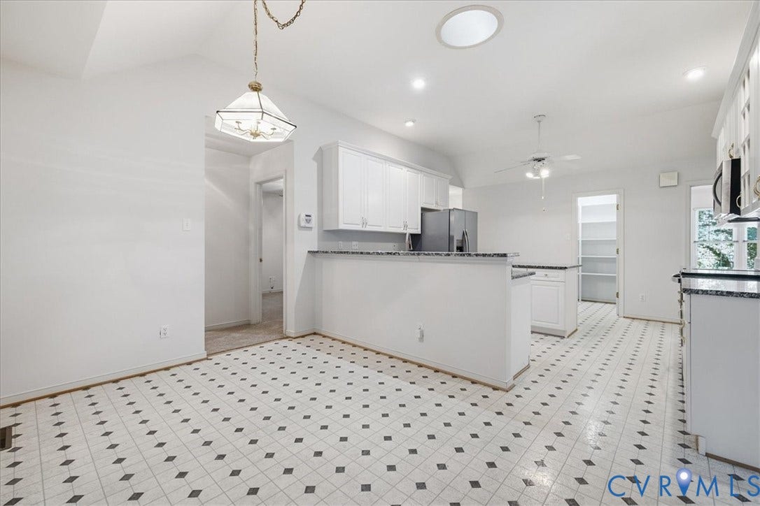 Kitchen featuring white cabinetry, granite countertops, stainless steel refrigerator, recessed lighting, and a skylight