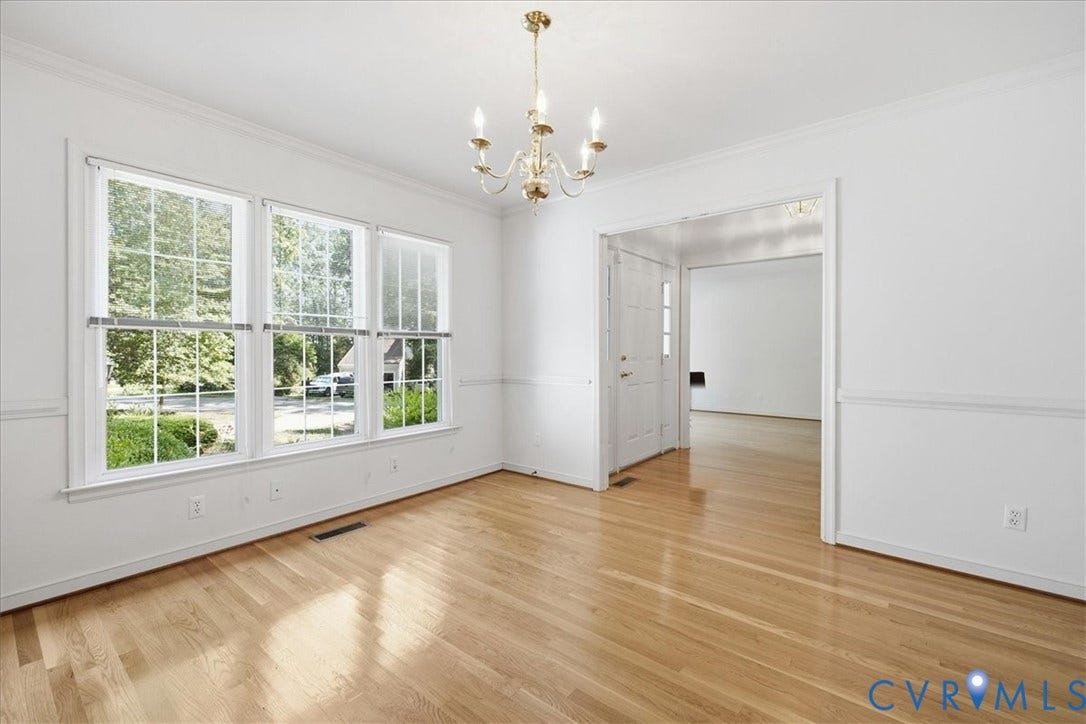 Hardwood flooring, triple windows with grid inserts, crown molding, chair rail molding, and a brass-tone chandelier
