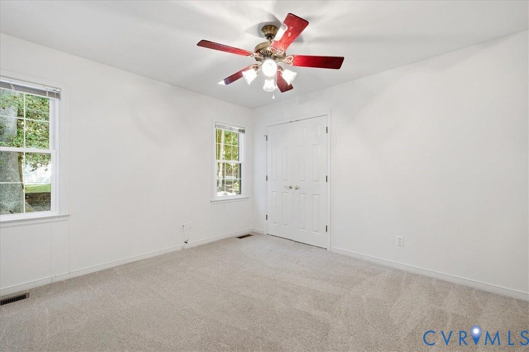 Carpeted room featuring two windows, a ceiling fan with integrated lighting, and bi-fold closet doors