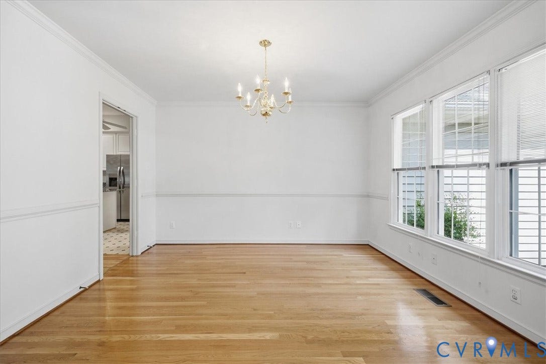 Hardwood flooring, a multi-pane window, crown molding, chair rail molding, and a brass-tone chandelier