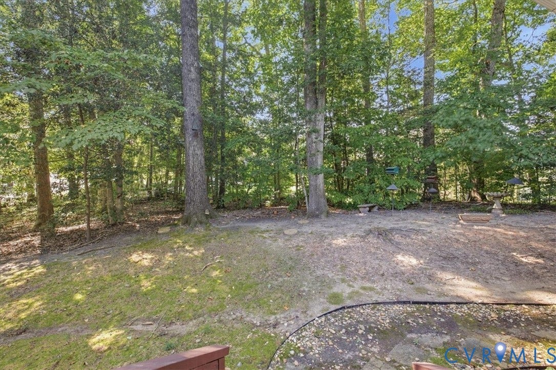 Wooded backyard featuring mature trees and a stone-look patio