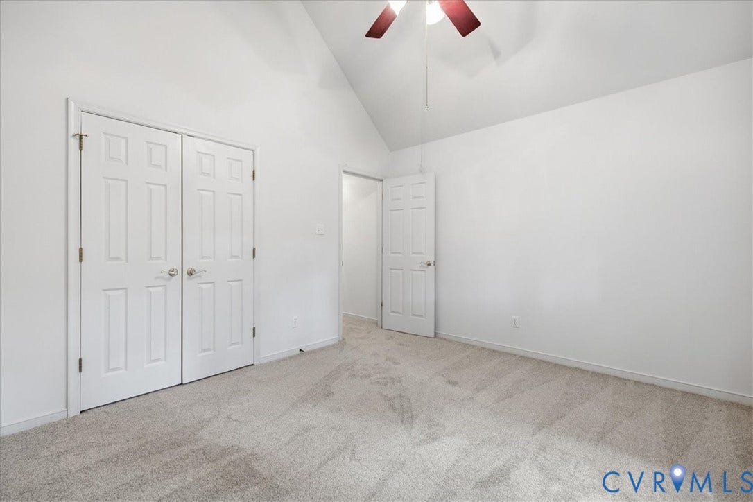 Vaulted ceiling with a ceiling fan, neutral wall paint, and gray carpet flooring