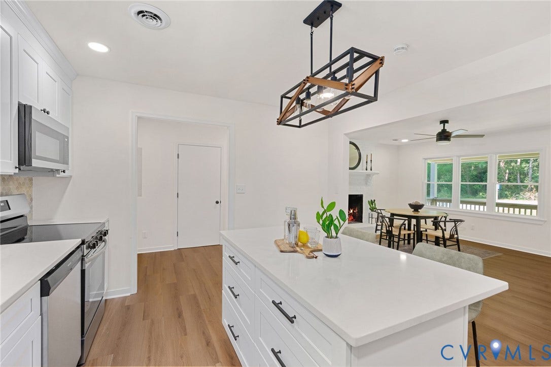 Open-concept kitchen with white cabinetry, stainless steel appliances, and a central island with a solid surface countertop