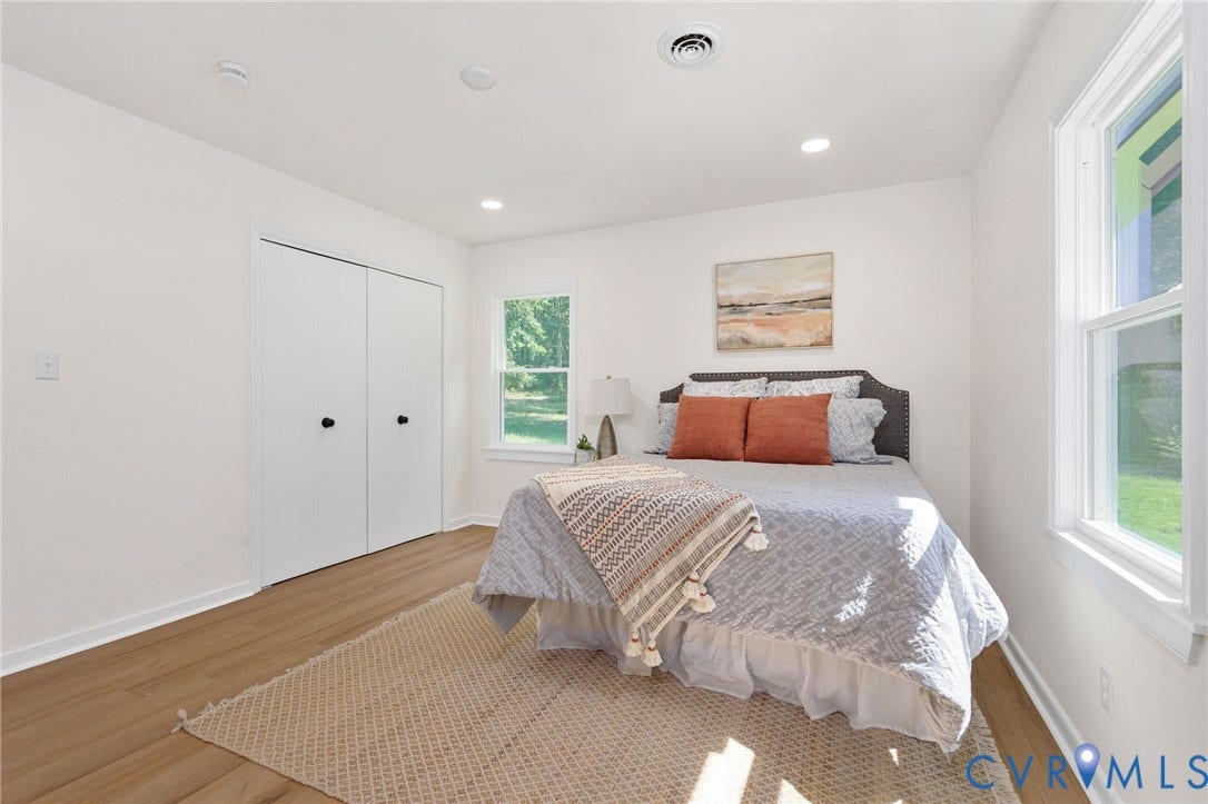 Bright interior with wood-finish flooring, two large windows, white bi-fold closet doors, and recessed lighting