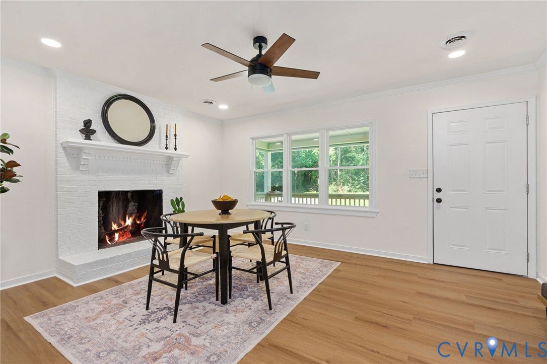 White painted brick fireplace with a classic mantel, wood-finish flooring, recessed lighting, and a multi-pane window