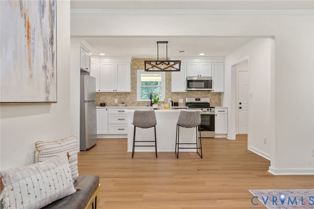Kitchen featuring wood-finish flooring, white cabinetry, stainless steel appliances, and a tiled backsplash
