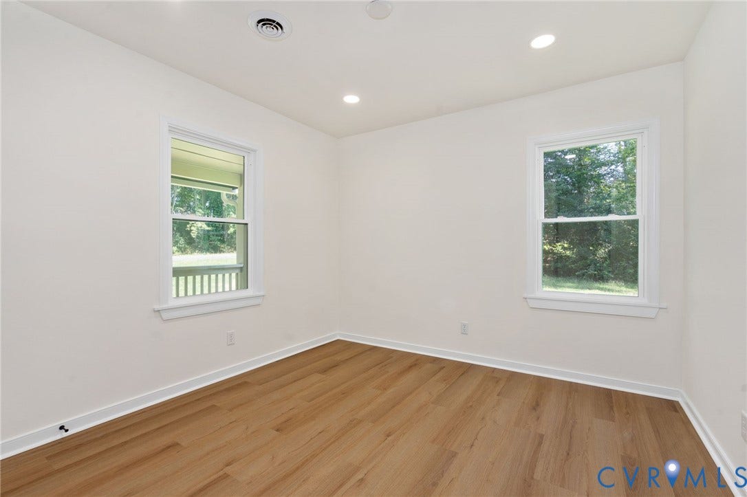 White walls, wood-finish flooring, two windows, and recessed lighting