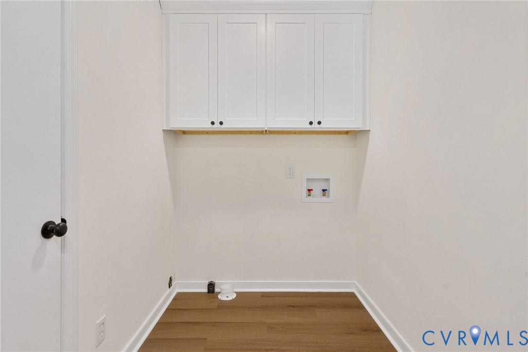 Laundry area with wood-finish flooring, white shaker-style cabinetry, and a utility hookup