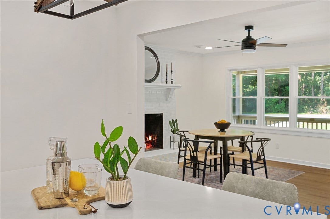 White brick fireplace with a decorative mantel, wood-finish flooring, and multiple windows