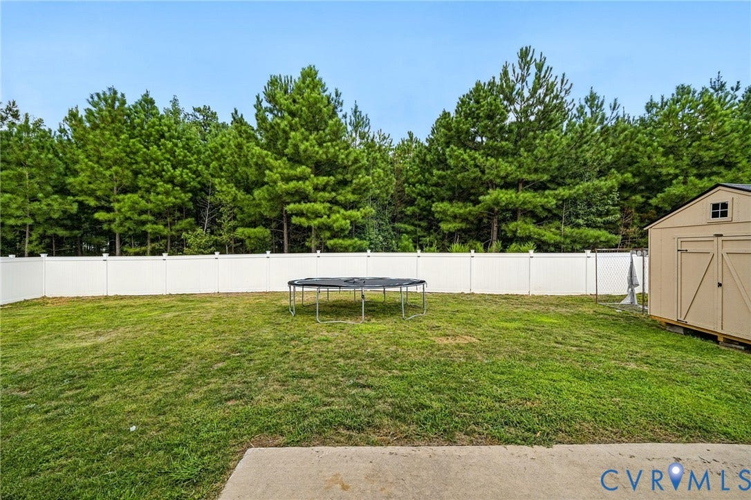 5713 Bison Ford Court, Chesterfield, VA 23234 Expansive backyard featuring a manicured lawn, a white privacy fence, and a storage shed
