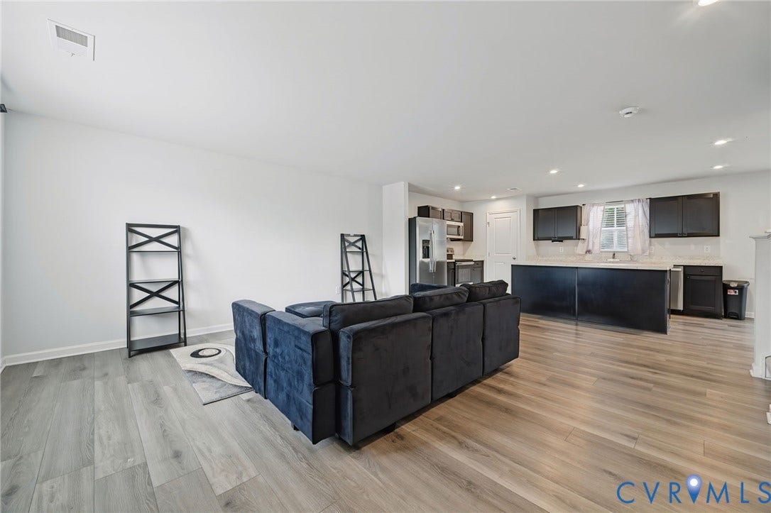 5713 Bison Ford Court, Chesterfield, VA 23234 Open-concept living space featuring wood-finish flooring, recessed lighting, and a kitchen with dark cabinetry, light countertops, and stainless steel appliances