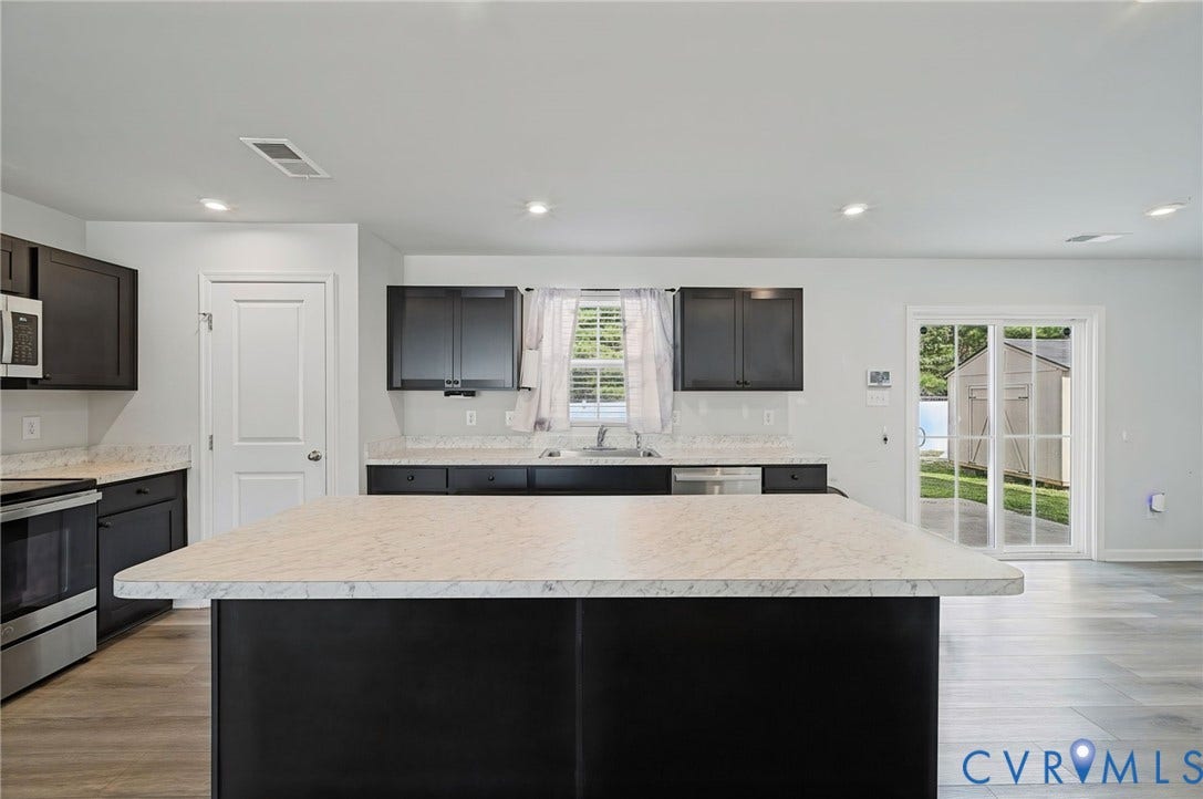 5713 Bison Ford Court, Chesterfield, VA 23234 Central island with a light-toned countertop, dark cabinetry, stainless steel appliances, wood-finish flooring, and sliding glass doors