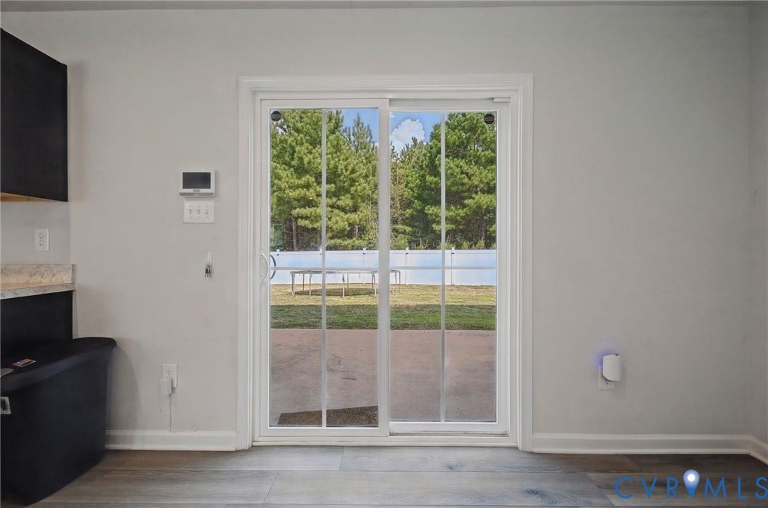 5713 Bison Ford Court, Chesterfield, VA 23234 Sliding glass door leading to an exterior patio with a white picket fence, wood-finish flooring, and light gray wall paint