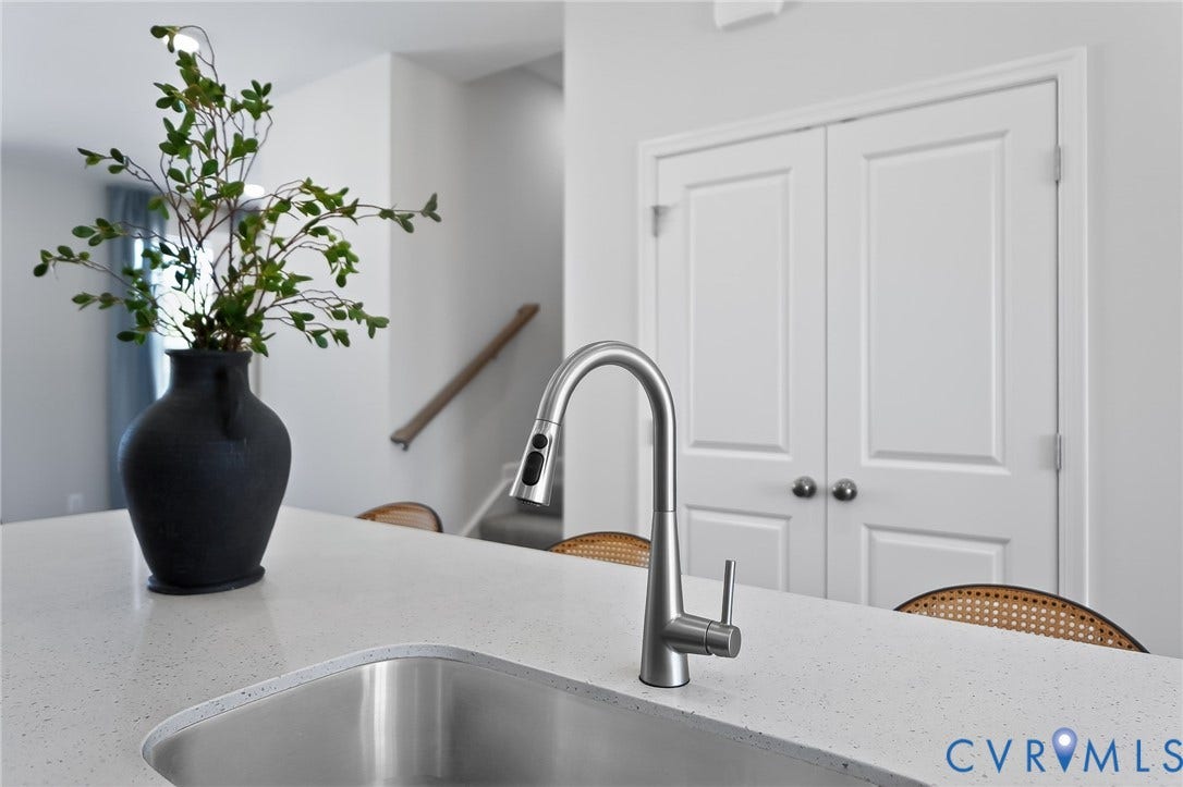 6138 Hull Street Road, Richmond, VA 23224 Stainless steel undermount sink with a gooseneck pull-down faucet, solid surface countertop, and white double panel doors