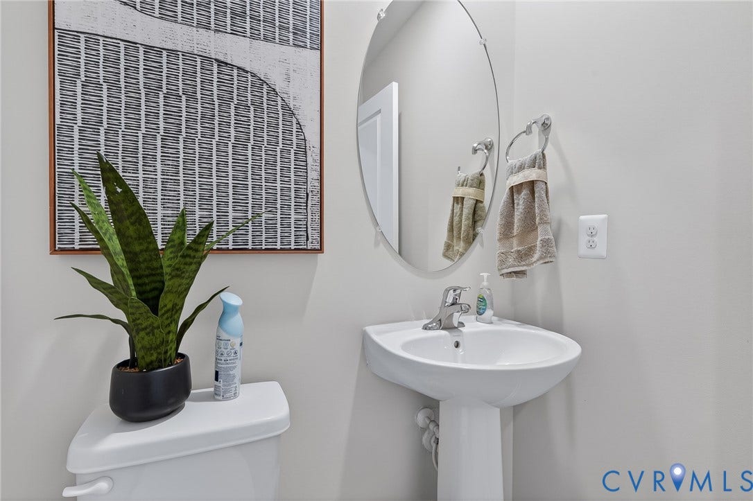 6138 Hull Street Road, Richmond, VA 23224 Pedestal sink with chrome faucet, oval wall-mounted mirror, and white toilet