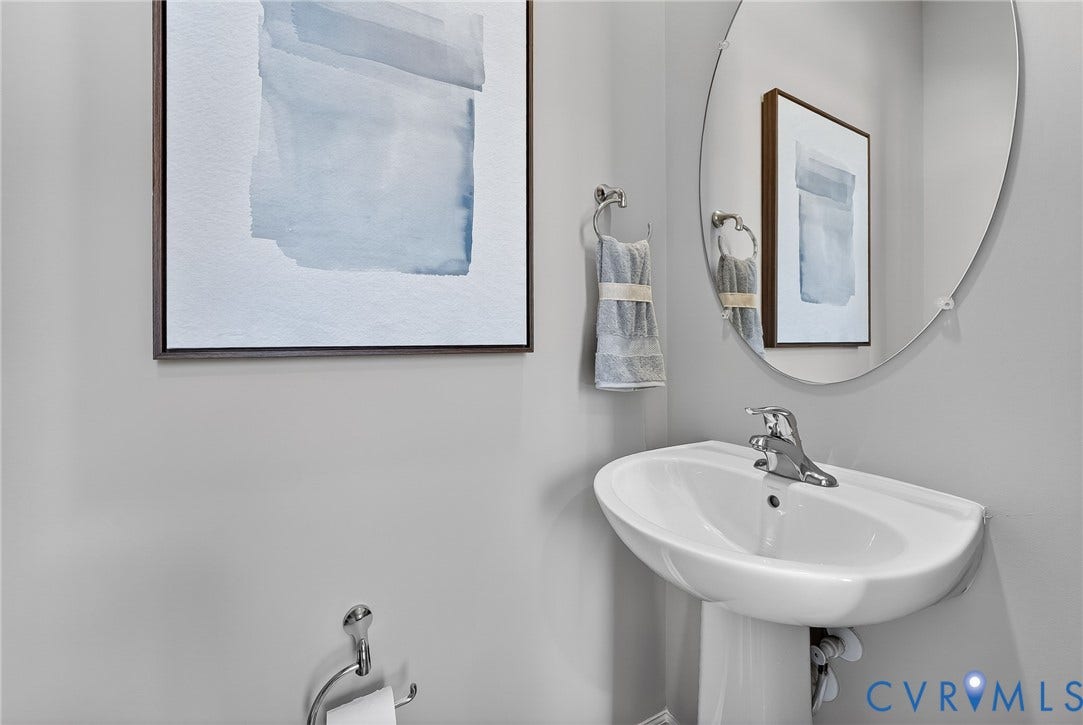 6138 Hull Street Road, Richmond, VA 23224 Pedestal sink with a chrome faucet, oval mirror, and chrome towel ring