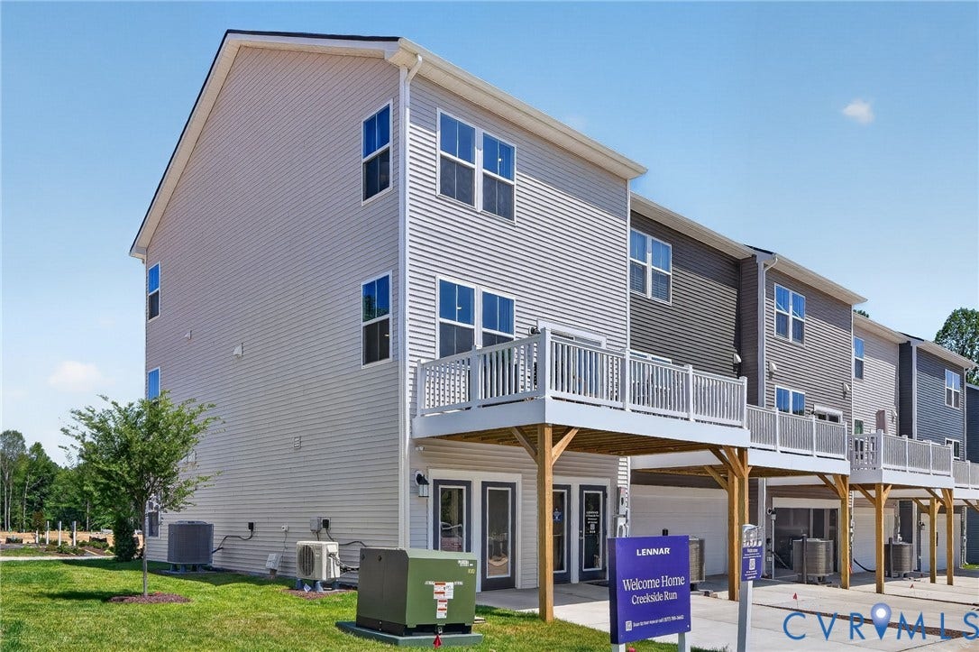 6138 Hull Street Road, Richmond, VA 23224 Multi-level townhome featuring light-colored siding, a white railing balcony, and a ground-level patio