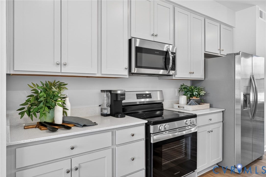 6138 Hull Street Road, Richmond, VA 23224 White shaker cabinetry, light-toned countertops, stainless steel appliances, and wood-finish flooring