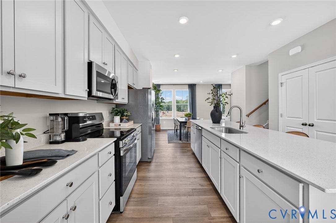 6138 Hull Street Road, Richmond, VA 23224 Galley kitchen featuring white cabinetry, light countertops, wood-finish flooring, stainless steel appliances, and recessed lighting
