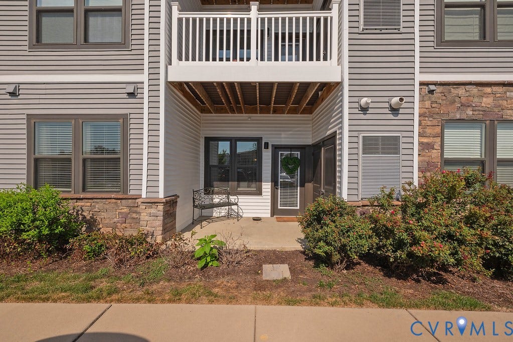 4000 Maze Runner Drive, #101, Midlothian, VA 23112 Ground-level entry with a covered patio, framed by stone veneer accents and a white railing balcony above