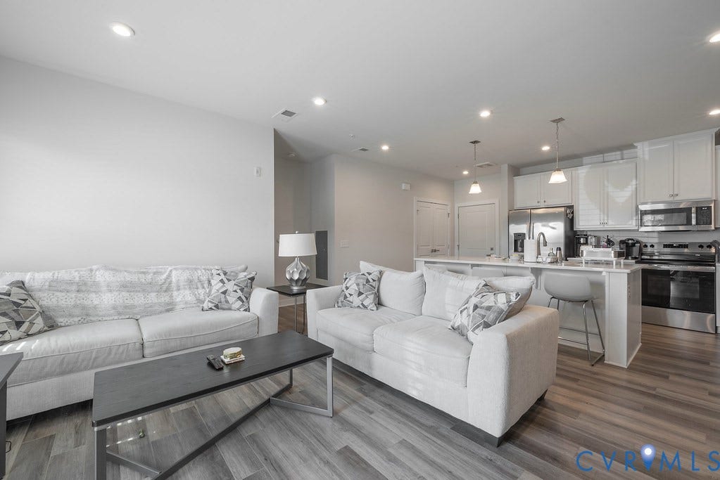 4000 Maze Runner Drive, #101, Midlothian, VA 23112 Open-concept living space featuring wood-finish flooring, recessed lighting, and a kitchen with white cabinetry, stainless steel appliances, and a breakfast bar