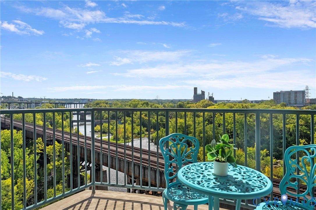 1101 Haxall Point, #U514, Richmond, VA 23219 Balcony with metal railing and concrete flooring overlooking a river, lush greenery, and distant structures