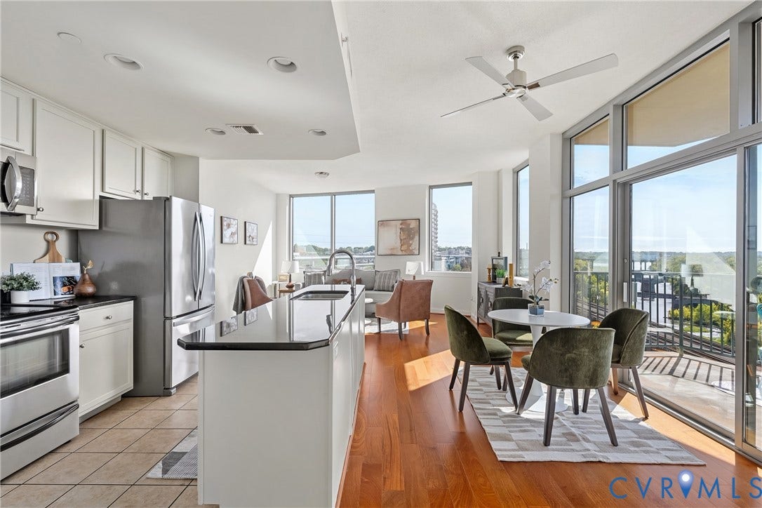 1101 Haxall Point, #U514, Richmond, VA 23219 Open-concept living space with wood-finish flooring, a kitchen island, stainless steel appliances, and extensive window walls