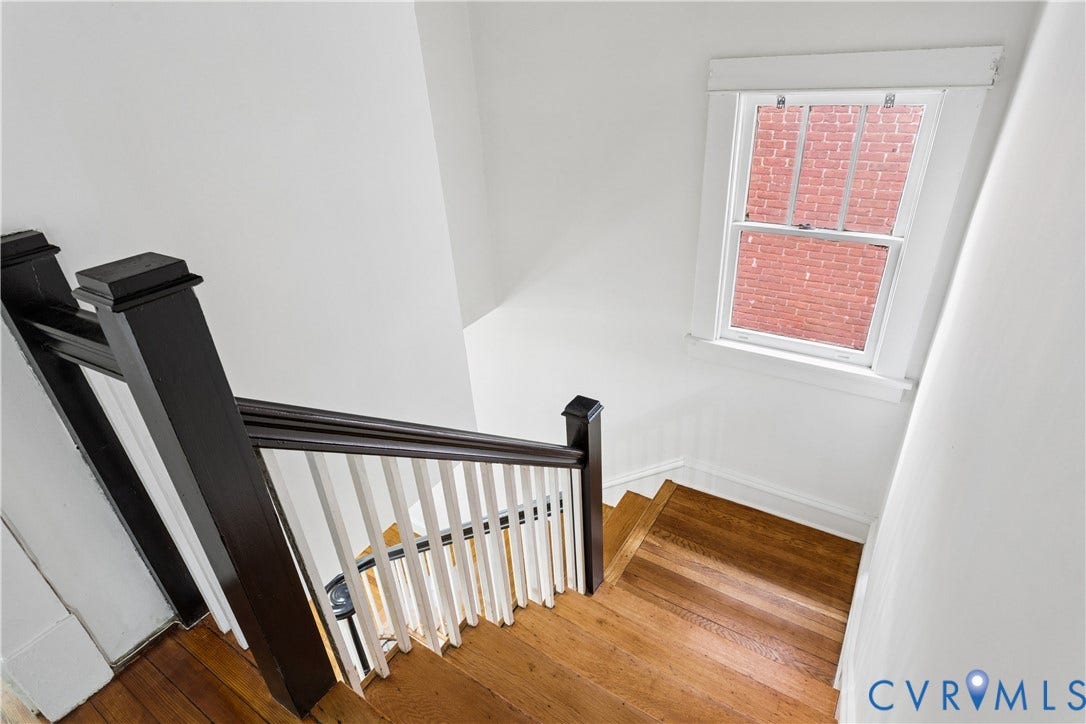 1304 Bainbridge Street, Manchester, Richmond, VA 23224 Hardwood stairs with dark wood newel posts and railings, white painted balusters, and a double-hung window with white trim