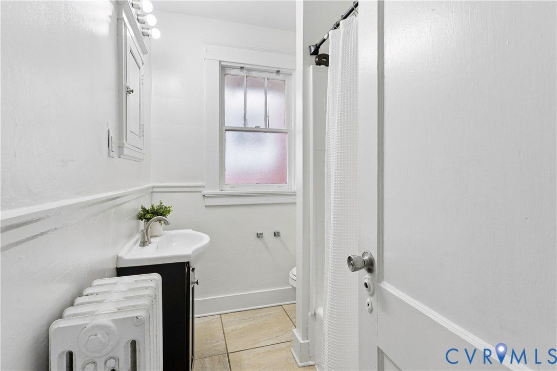 1304 Bainbridge Street, Manchester, Richmond, VA 23224 Corner vanity with integrated basin, tiled flooring, built-in medicine cabinet, and a window with privacy glass