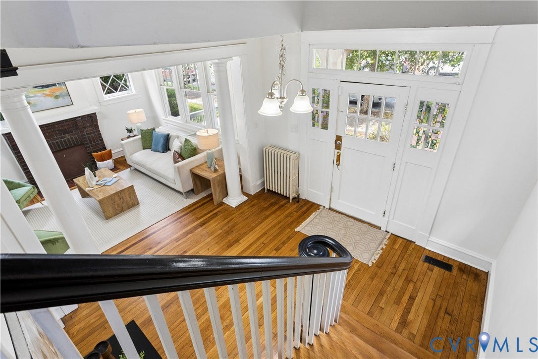 1304 Bainbridge Street, Manchester, Richmond, VA 23224 Hardwood flooring throughout, white painted staircase with dark wood railing, and an entry door featuring multiple window panes and a transom window