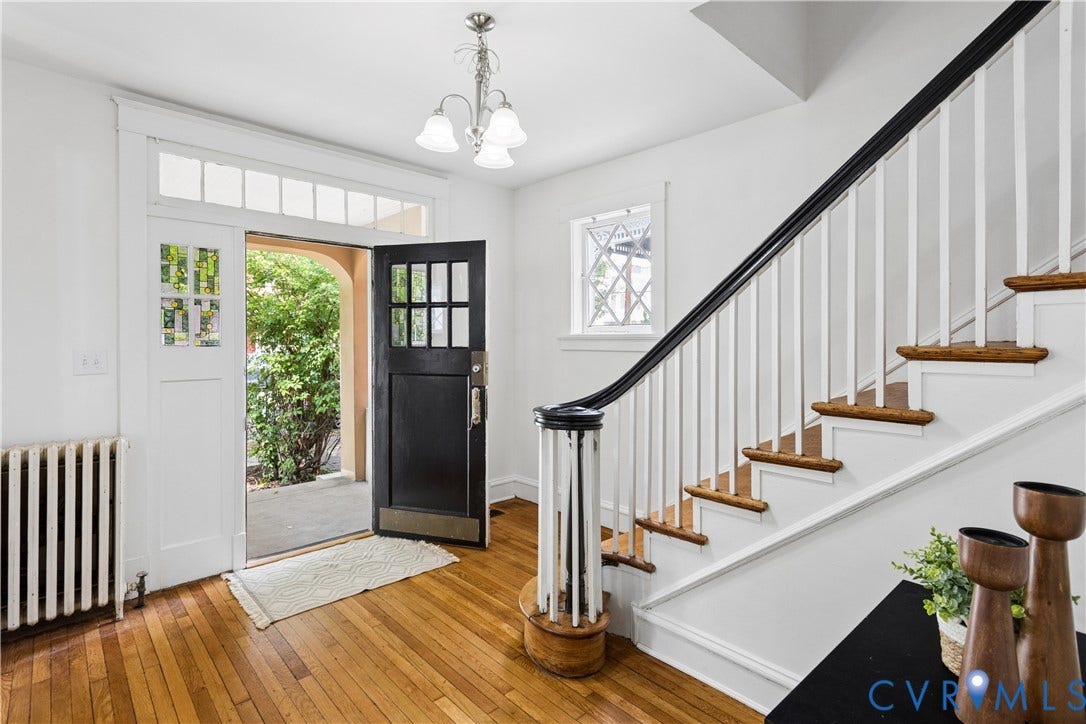 1304 Bainbridge Street, Manchester, Richmond, VA 23224 Hardwood flooring, classic black paneled door with glass inserts, transom window, traditional staircase with white balusters and dark wood handrail, vintage-style chandelier