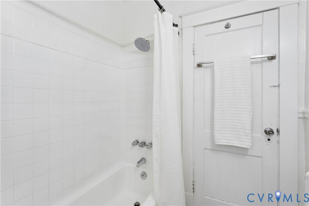 1304 Bainbridge Street, Manchester, Richmond, VA 23224 Bathtub with white tile surround, chrome showerhead, and integrated bath faucet