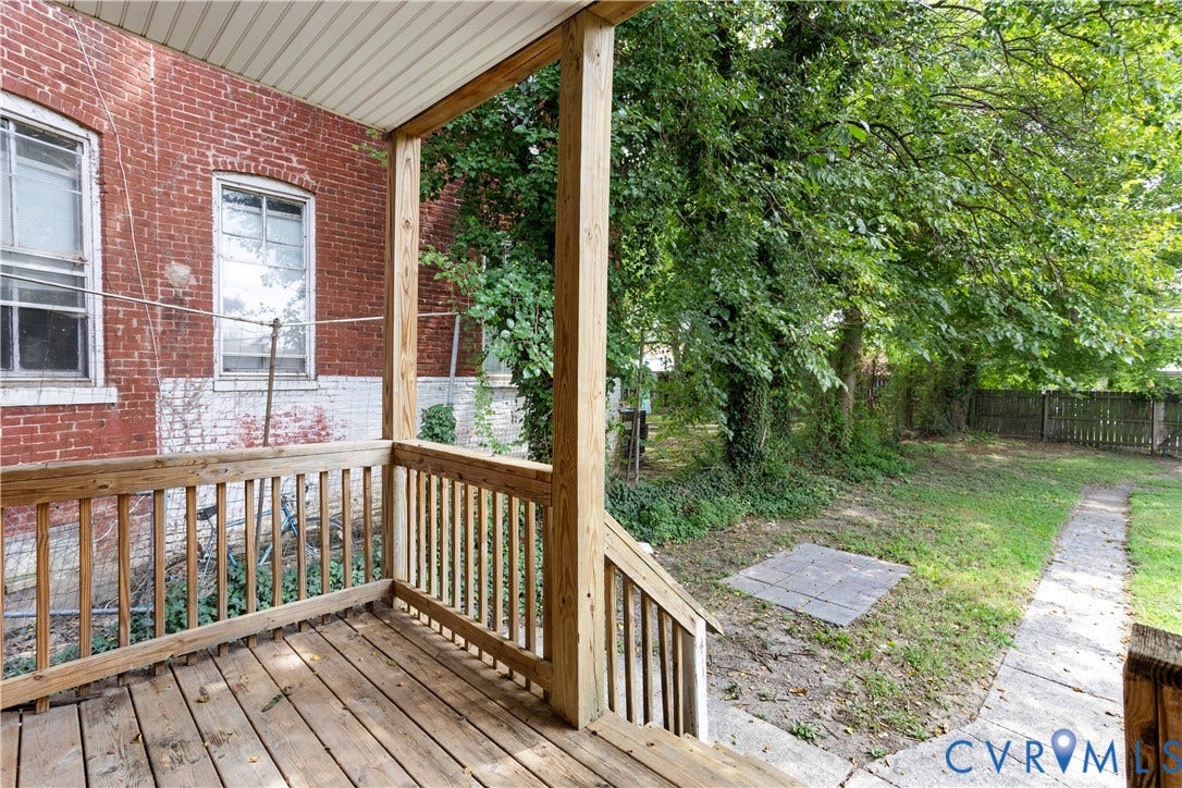 1304 Bainbridge Street, Manchester, Richmond, VA 23224 Wood-plank deck with wood railing, leading to a yard with mature trees and a paved walkway
