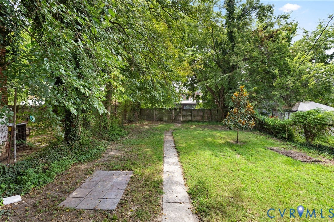 1304 Bainbridge Street, Manchester, Richmond, VA 23224 Expansive yard featuring a concrete paver pathway, mature trees, and a wood privacy fence