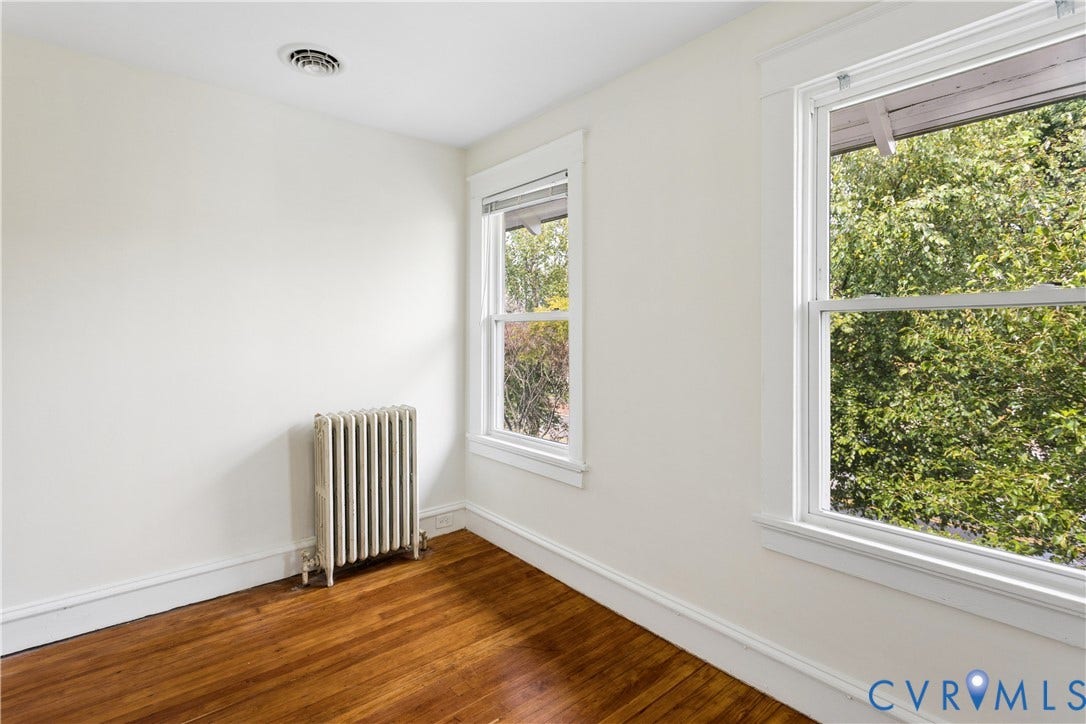1304 Bainbridge Street, Manchester, Richmond, VA 23224 Hardwood flooring, painted walls, two windows, baseboard trim, and a radiator