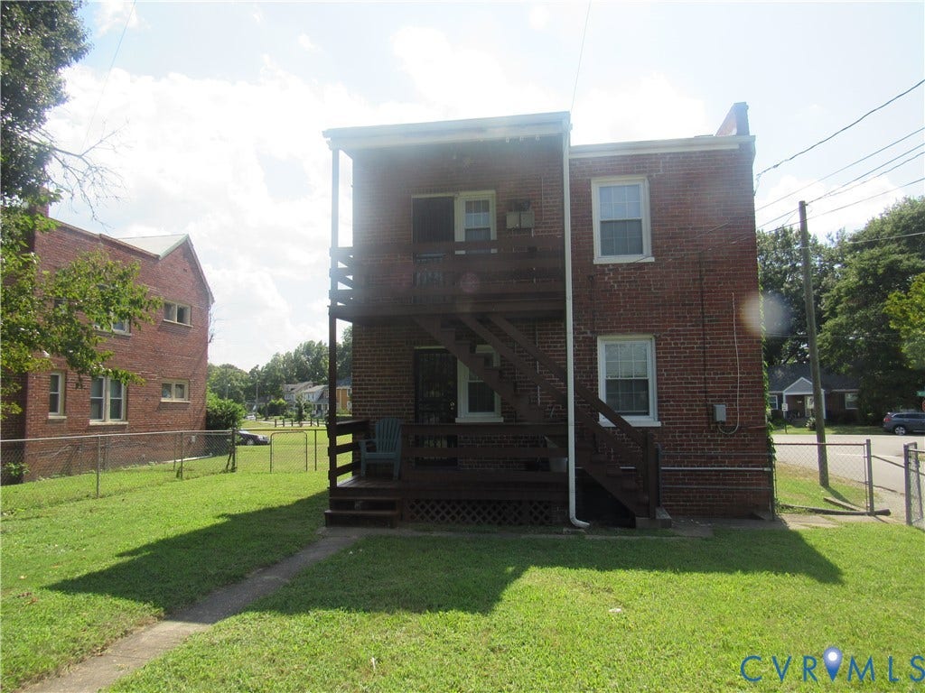 Brick exterior structure featuring a two-story wood deck and stairs