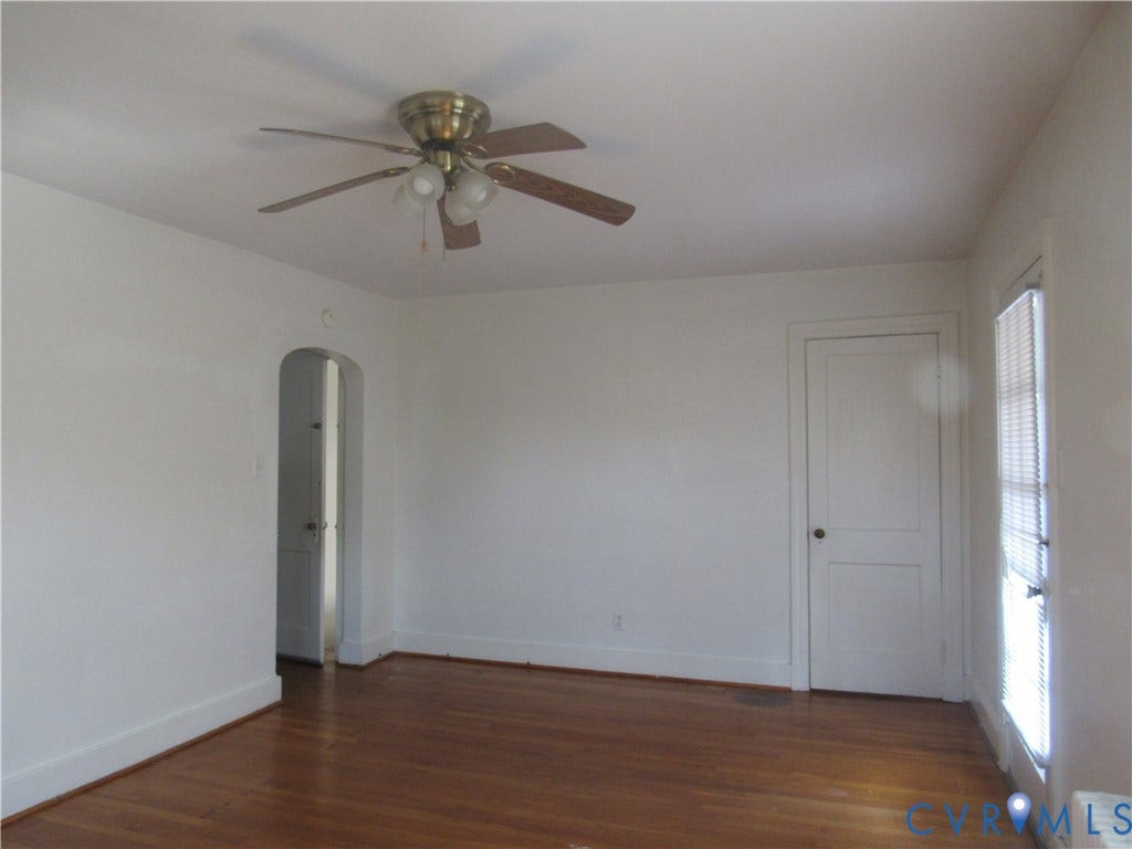 Hardwood flooring, arched doorway, ceiling fan with light fixture, window with blinds, white trim