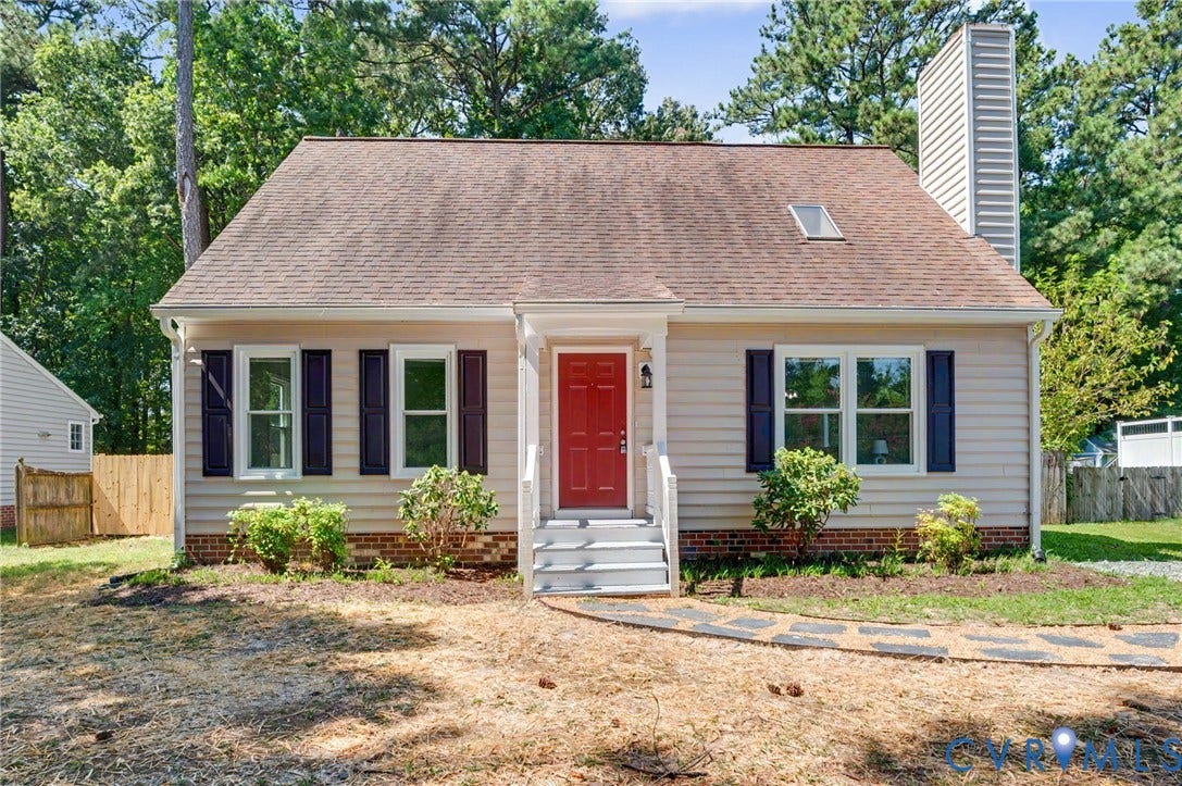 Siding exterior with a red entry door, white trim, and dark shutters