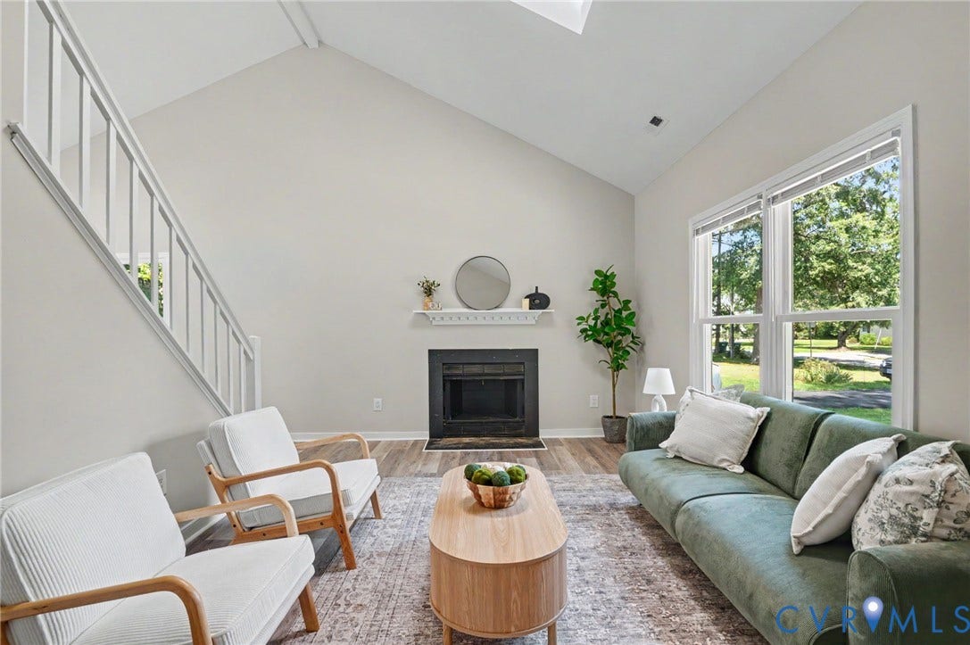 Vaulted ceilings, wood-finish flooring, and a fireplace with a white mantel
