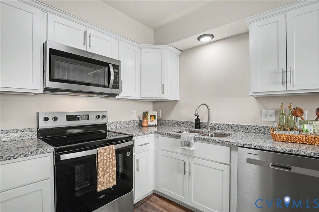 Kitchen featuring white shaker-style cabinetry, stainless steel appliances, speckled countertops, and a stainless steel sink with a gooseneck faucet