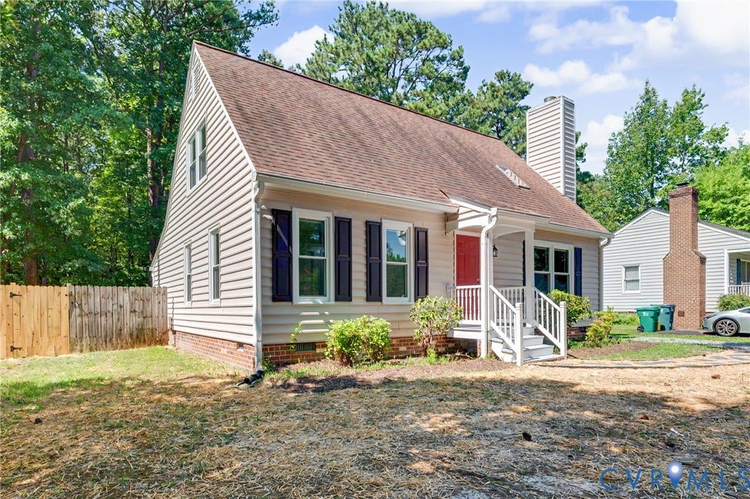 Exterior featuring horizontal siding, a gabled roofline, a front porch with white railing, a red entry door, and a privacy fence