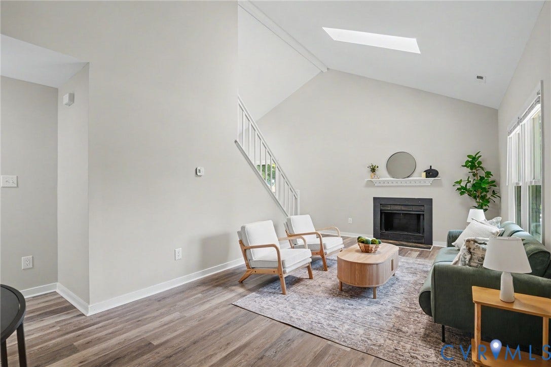 Vaulted ceiling, skylight, wood-finish flooring, staircase with white railing, and a fireplace with a white mantel