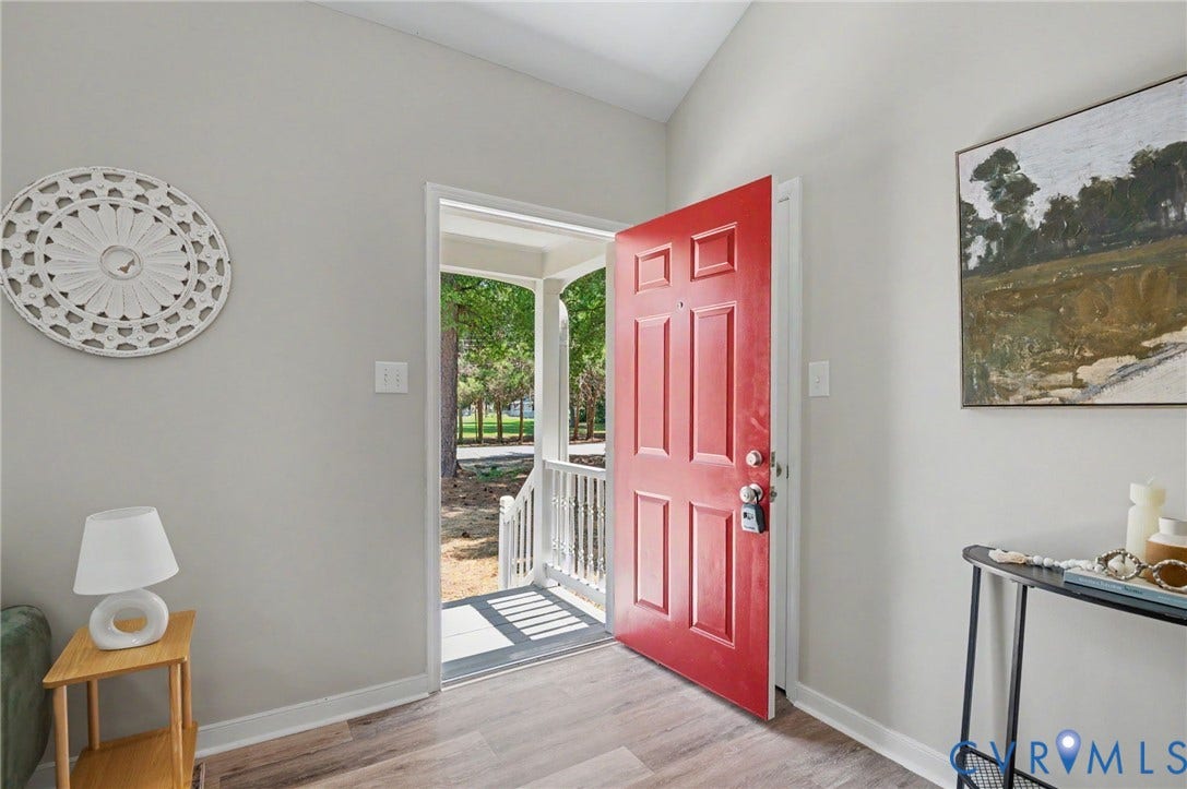 Red panel door with brushed nickel hardware, wood-finish flooring, and light gray wall paint