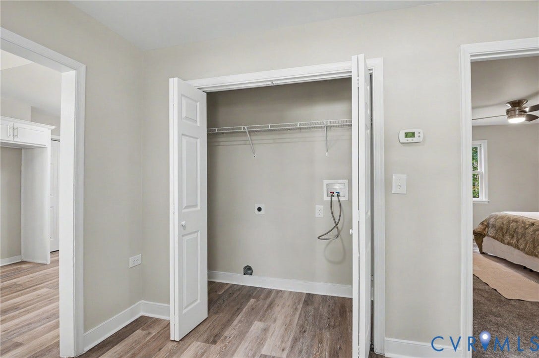 Laundry closet with bi-fold doors, wire shelving, and wood-finish flooring
