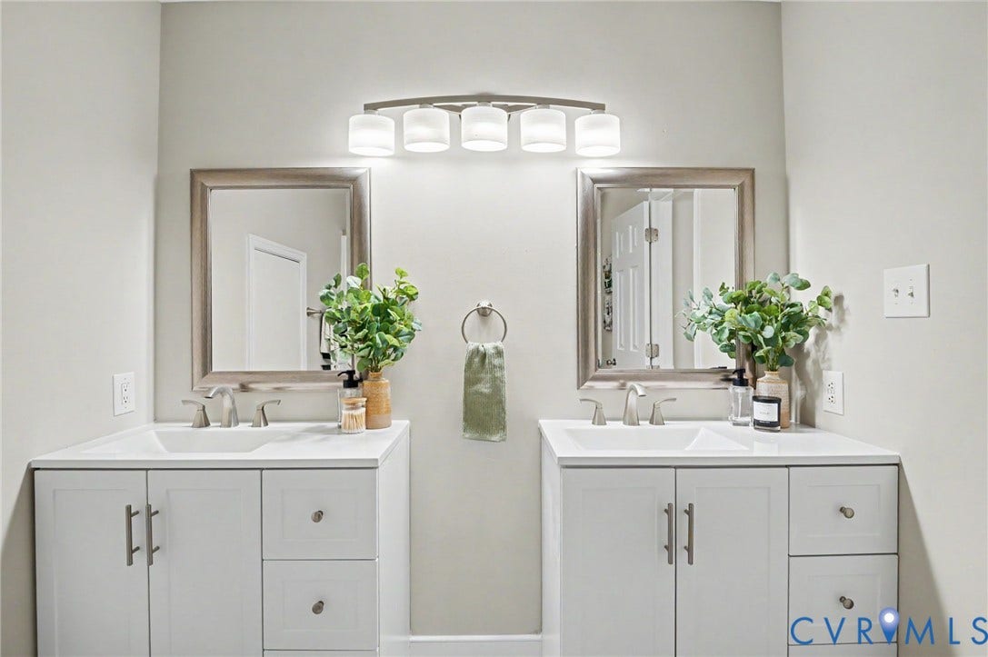 Dual vanity with white cabinetry, integrated sinks, brushed nickel fixtures, and framed mirrors