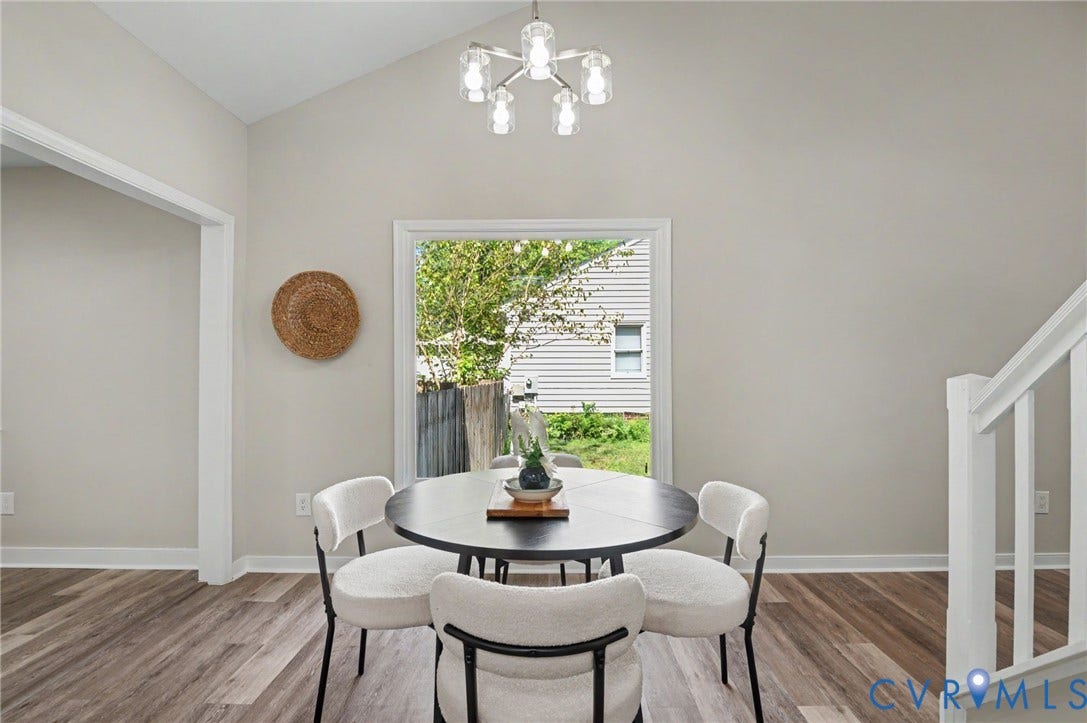 Elegant dining space showcasing a round black table, cream upholstered chairs, and hardwood flooring throughout
