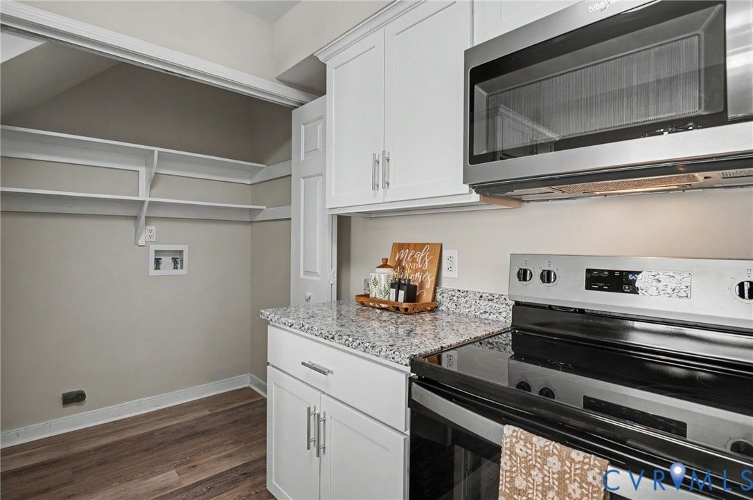 White cabinetry with brushed nickel hardware, speckled countertops, stainless steel appliances, wood-finish flooring, and built-in shelving
