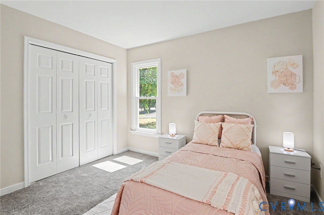 Neutral-toned walls, plush grey carpet, and a double-hung window provide natural illumination