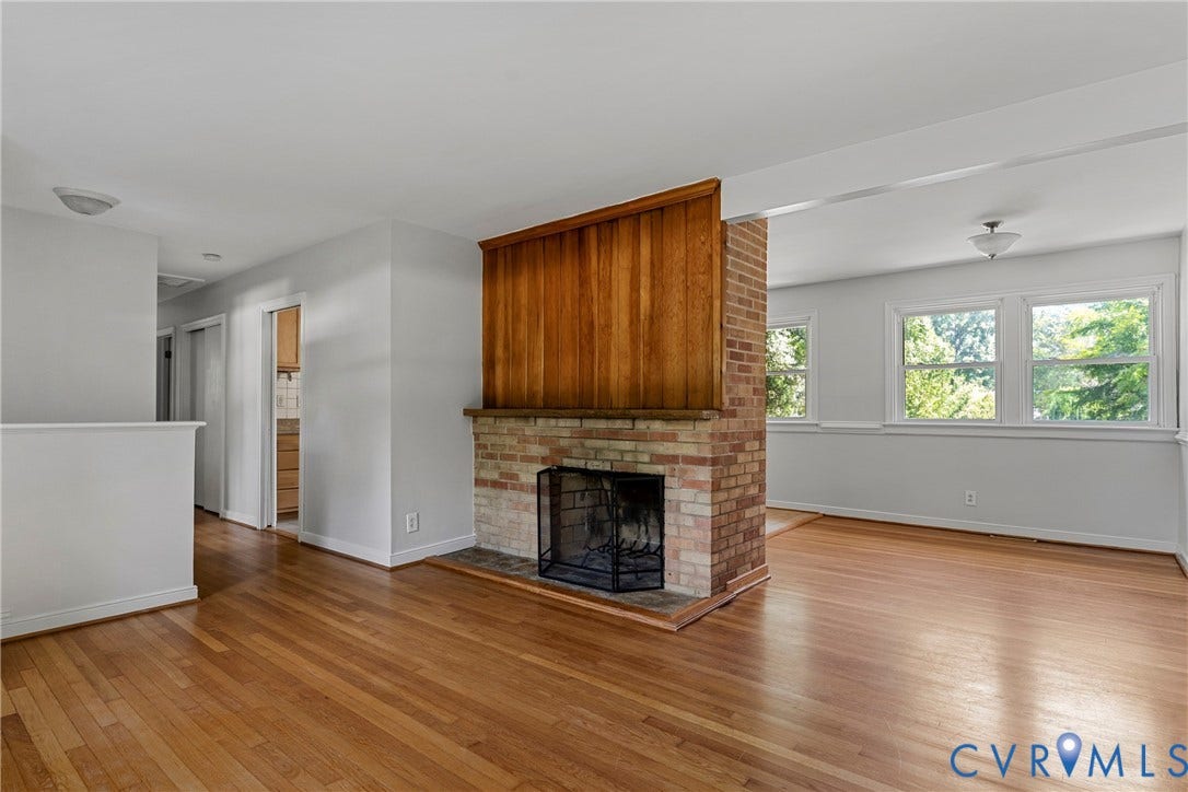 5968 Forest Hill Avenue, Westlake Hills, Richmond, VA 23225 Wood-finish flooring throughout, brick fireplace with wood paneling, multiple windows, and a semi-flush ceiling light fixture